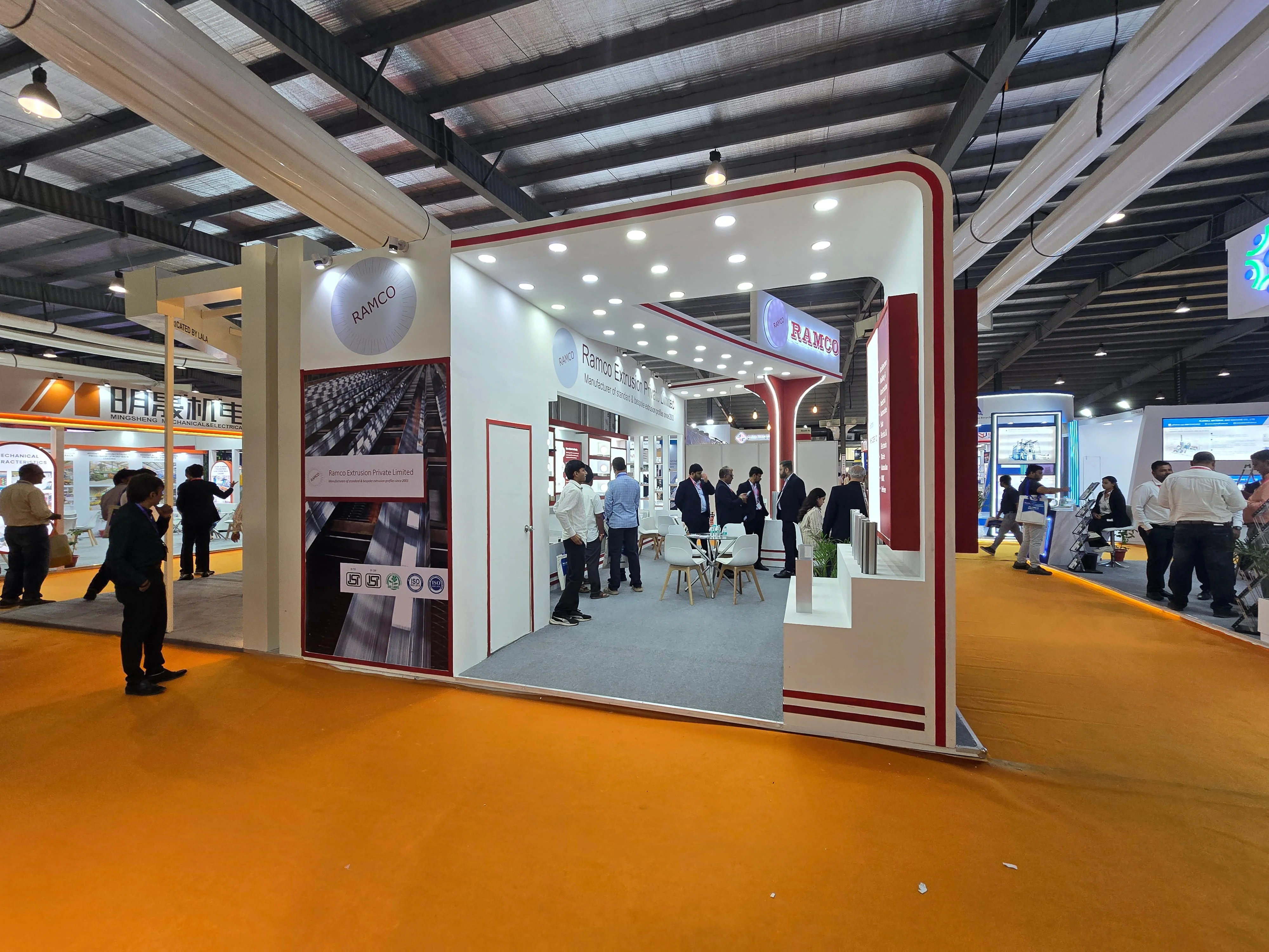 ndustrial exhibition booth with branded product displays, reception counter and seating.